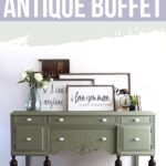 Olive green antique buffet with dark legs, decorated with flowers, art, and books against a white wall.