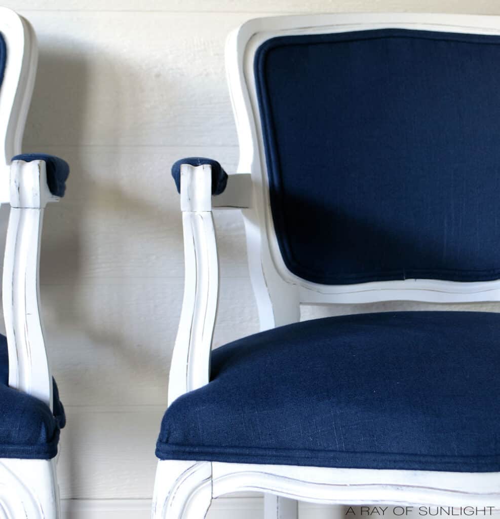 closeup of cane back chair covered with navy blue fabric and double welting