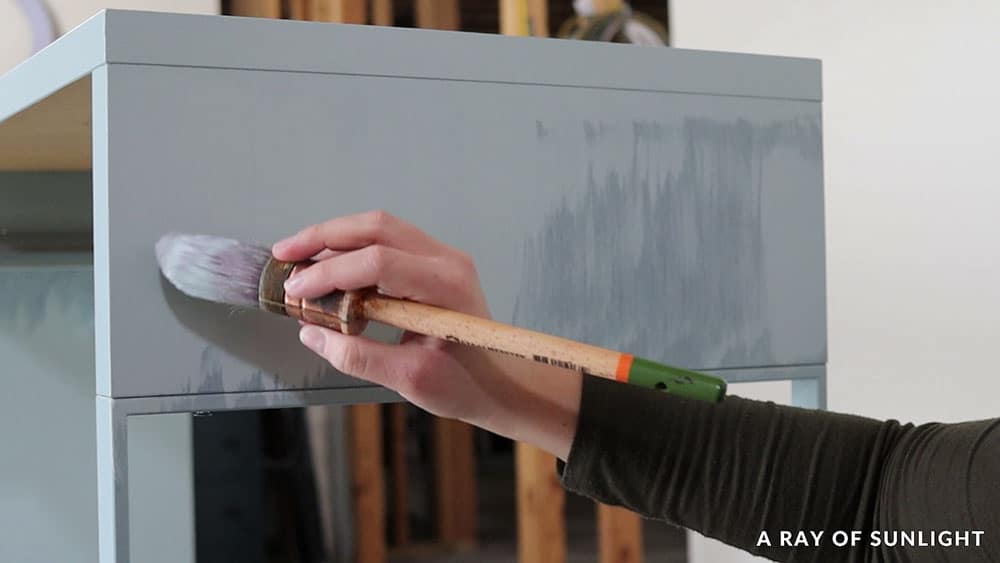 Brushing Fusion Mineral Paint onto a laminate IKEA desk.