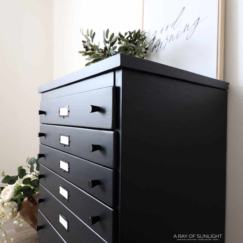 Side view of flat file cabinet with black paint and black knobs and label holders.