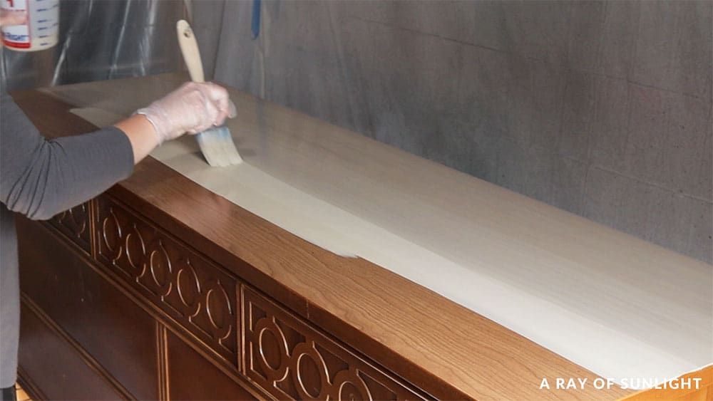 Brushing thinned-out paint onto the top of the dresser.