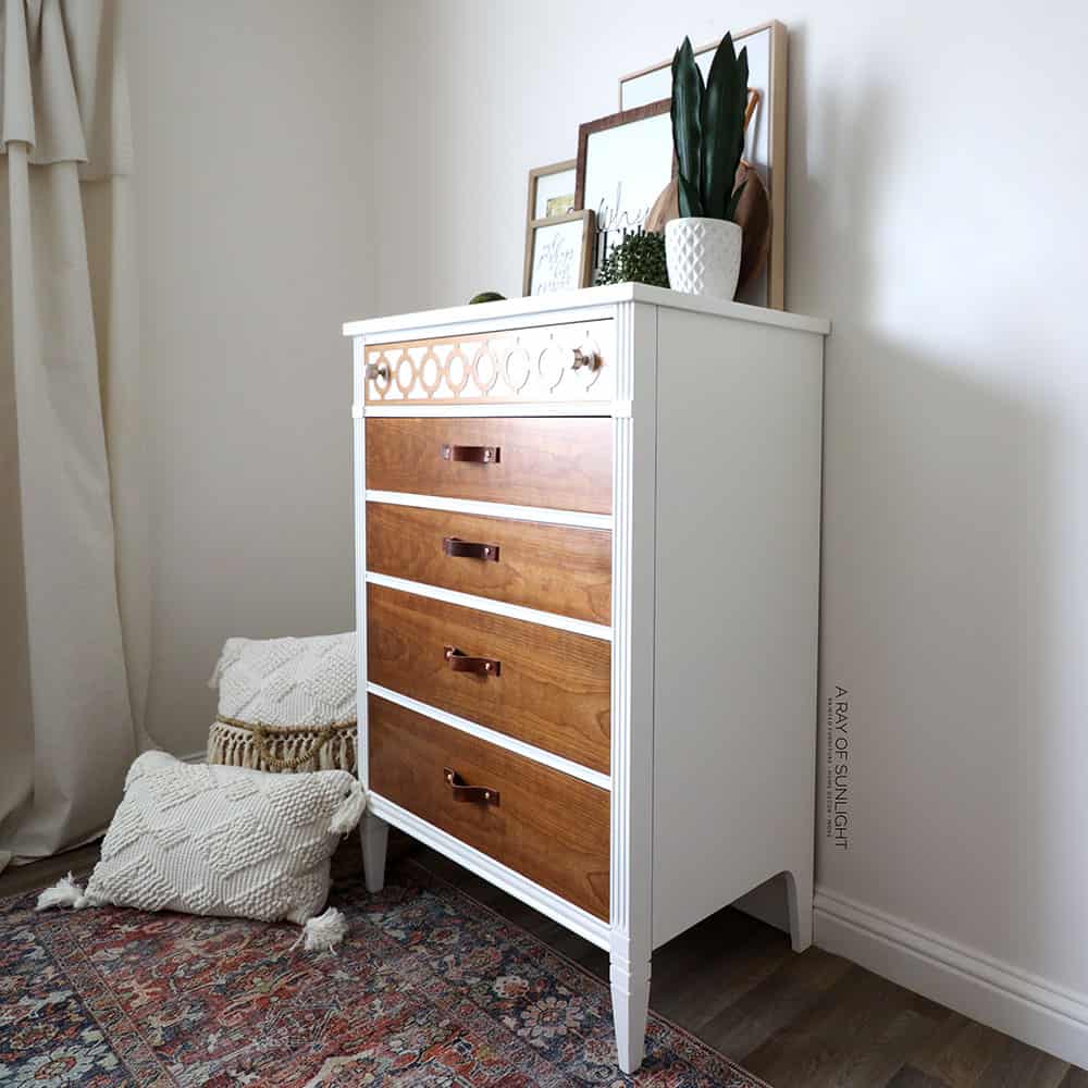 Angled full view of white dresser with wood drawers.