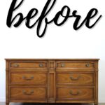 A wooden dresser with six drawers sits below the word before written in bold script on the wall.