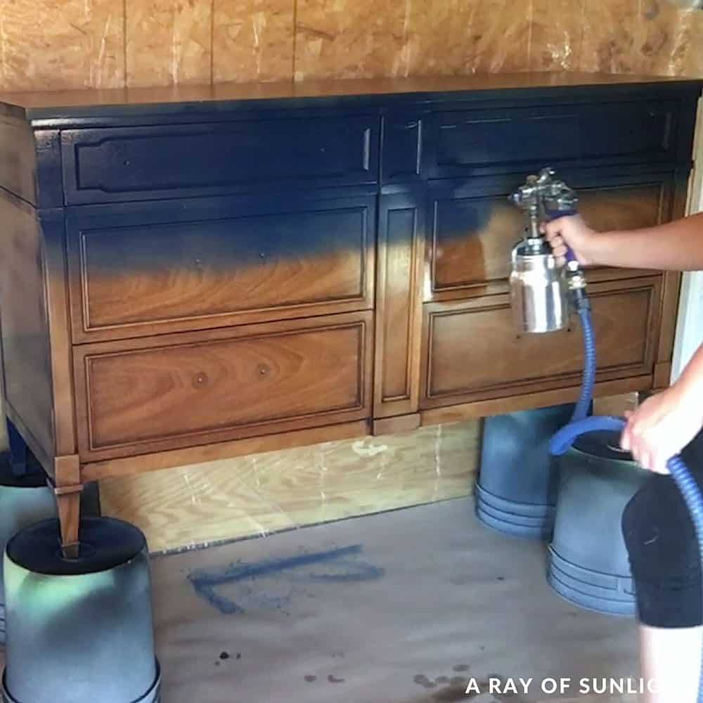 spraying the dresser with the fuji paint sprayer and navy blue chalk paint