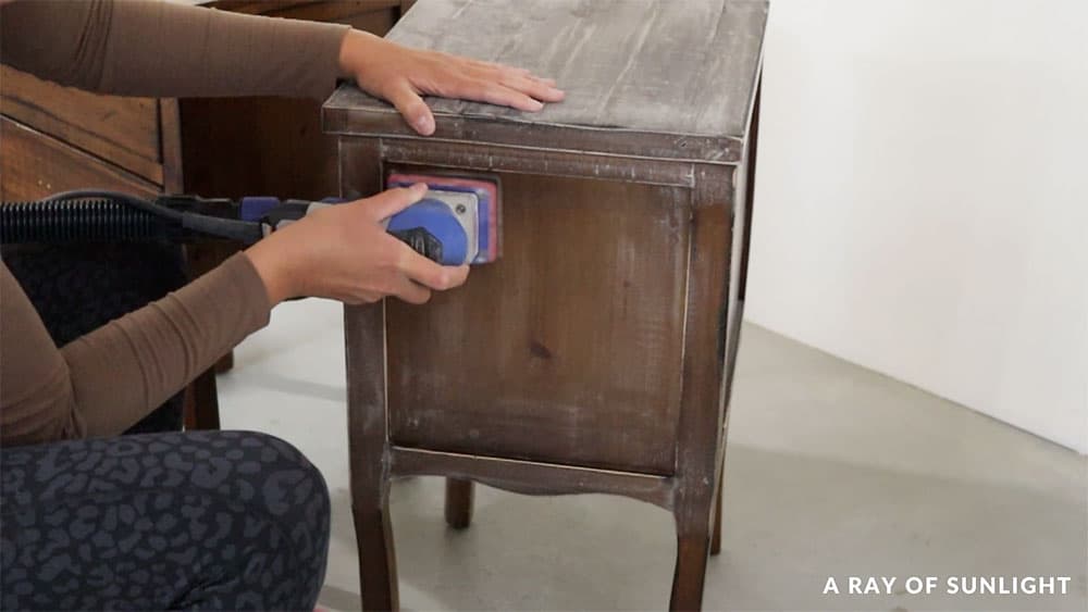 Scuff sanding nightstands with a power sander before painting