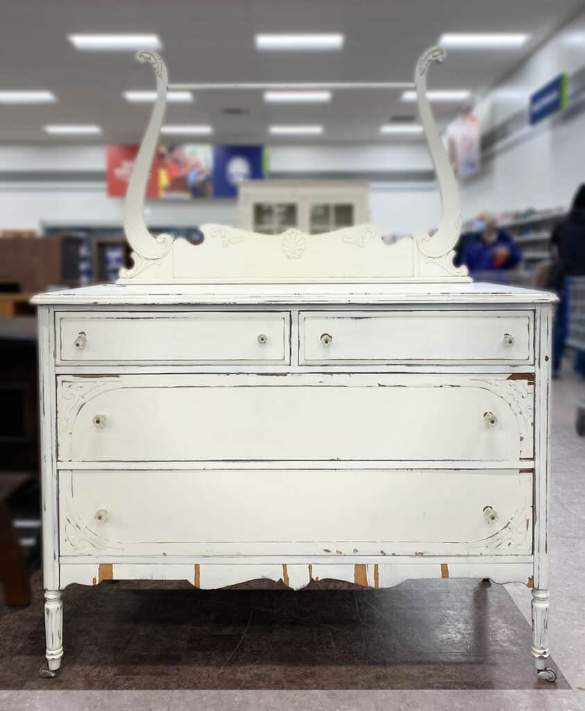 Beat up old white dresser with veneer chipping off.