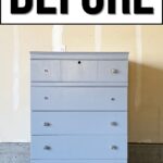 A plain, light blue dresser with mismatched knobs under a bold “BEFORE” label in a garage setting.