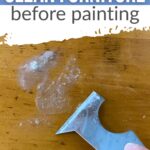 Hand scraping soapy bubbles off wooden furniture with a scraper