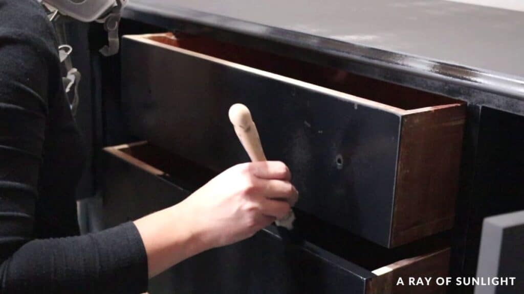 Touching up the drawer tops and edges with black chalk paint and a paint brush.