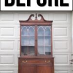 A vintage wooden china cabinet stands in front of a garage door with a large BEFORE sign above it.