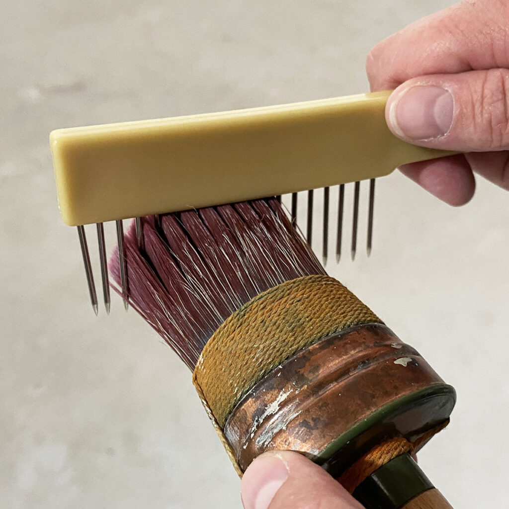 Cleaning a paint brush with a paint brush comb