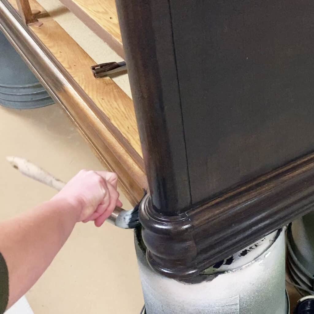 brushing paint onto a dresser in the details and trim