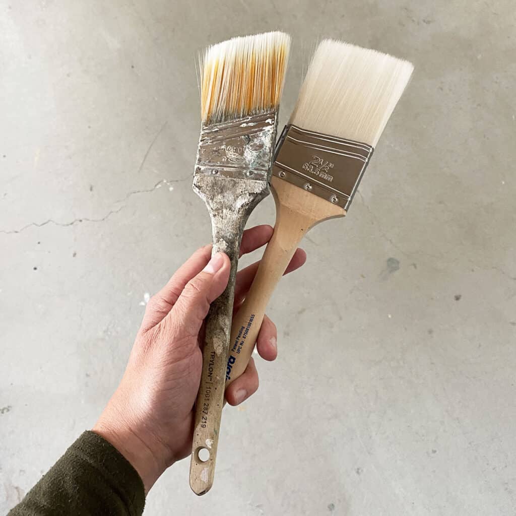 Two different paint brushes being held in a hand.