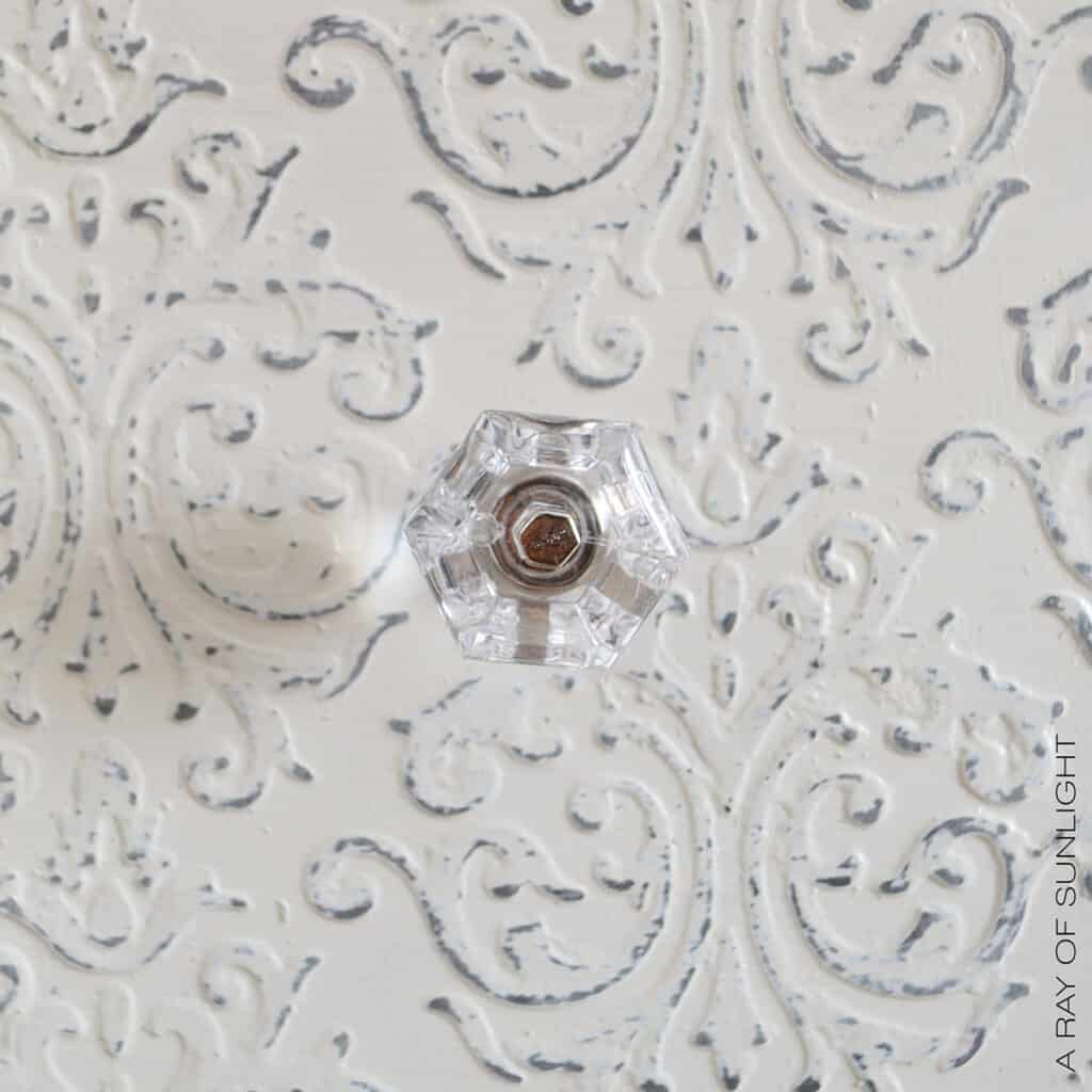 closeup of crystal knob with embossing in the background