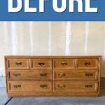 A long wooden dresser with brass handles in a garage