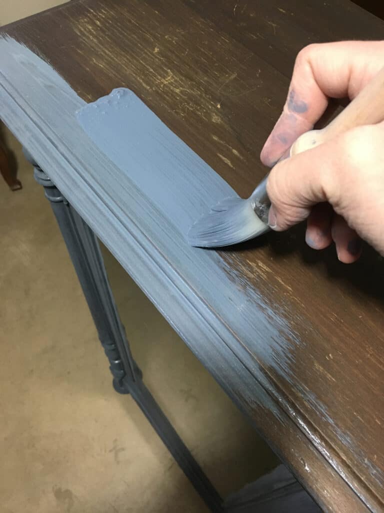 brushing milk paint onto the cabinet with a zibra fan brush