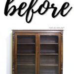 A vintage wooden cabinet with glass doors and shelves, labeled before in large script above it.