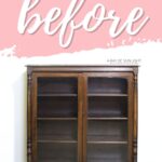 A dark wood cabinet with glass doors sits under a pink before sign on a white wall.