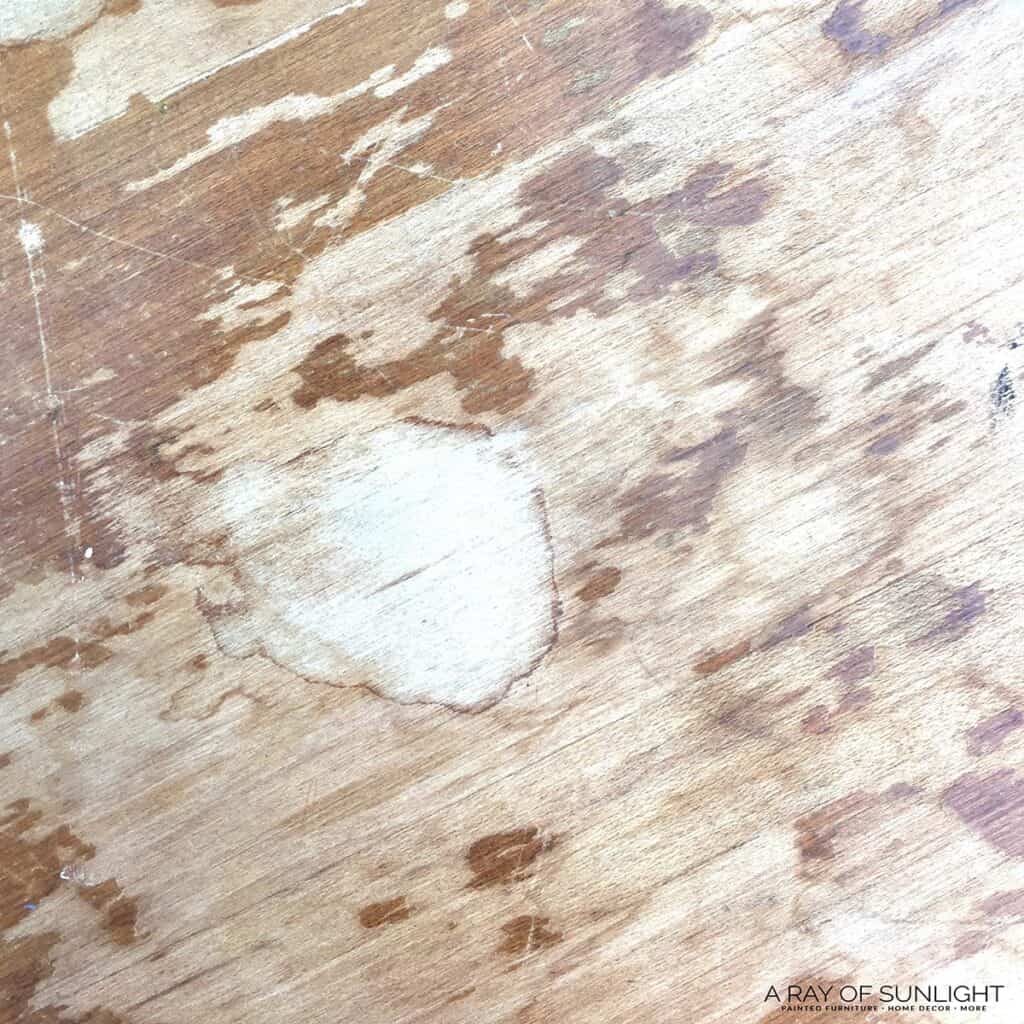 worn out wood nightstand top with scratched finish and water damage