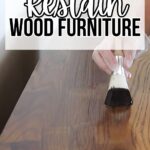 Hand applying stain to wooden furniture with a brush. Text reads How to Restain Wood Furniture.