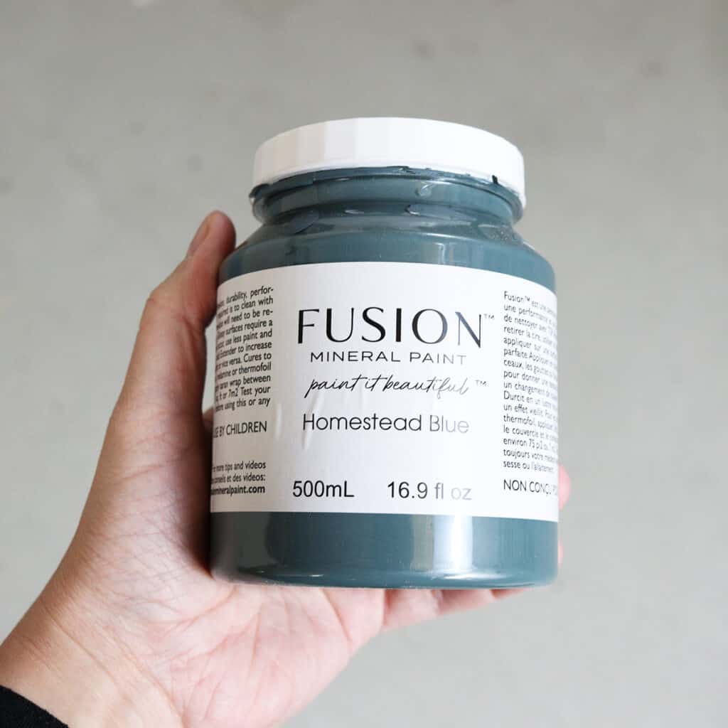 holding jar of fusion mineral paint in the color homestead blue