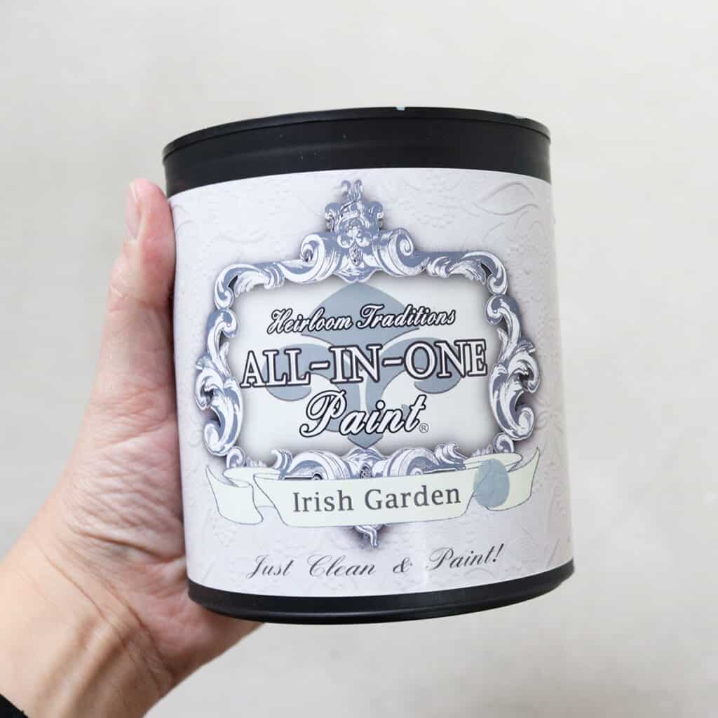 Holding can of heirloom traditions all-in-one paint in the color Irish garden