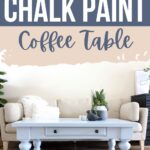 Light blue chalk-painted coffee table in front of a beige sofa, with plants and books on top.