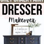 A dark grey dresser with gold handles, styled with a plant and decor, against a white wall.