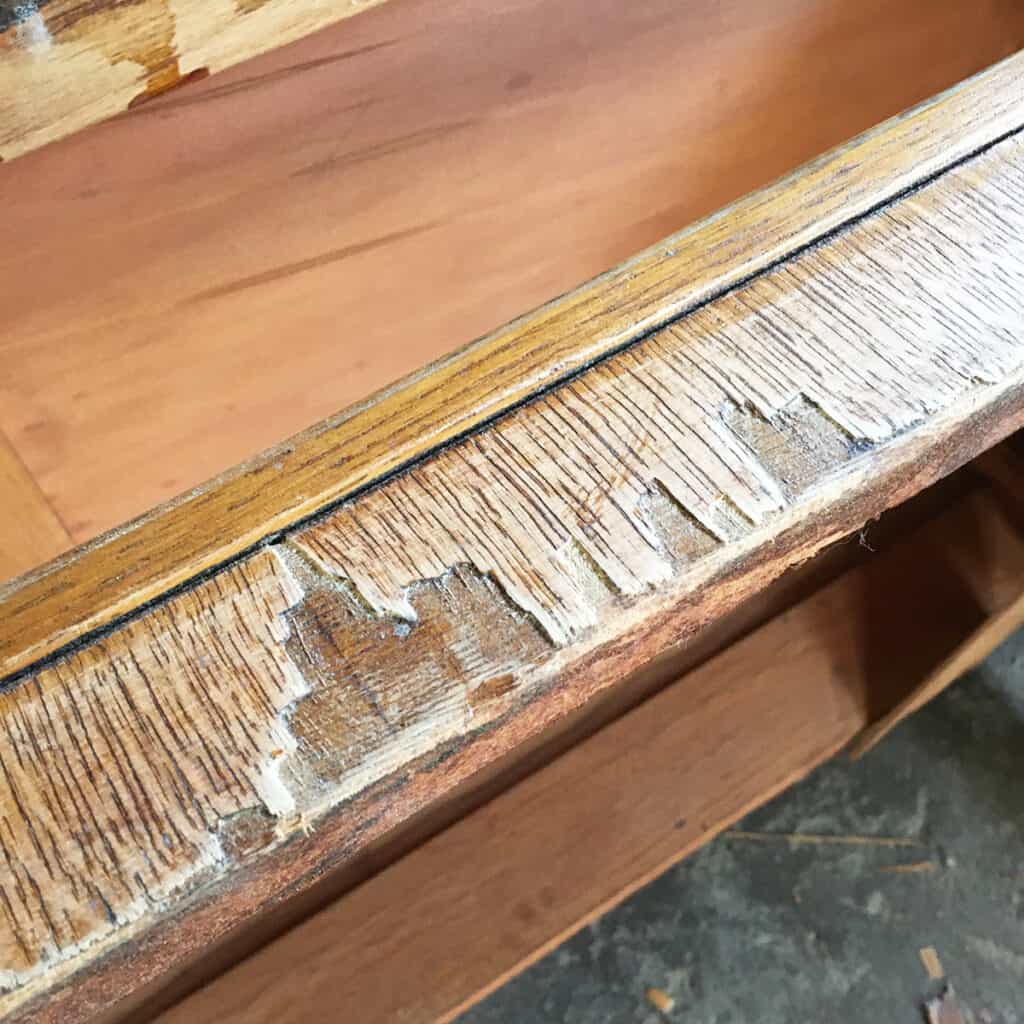 chipped veneer at the bottom of the furniture
