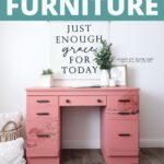 A pink painted desk with black handles with floral transfers