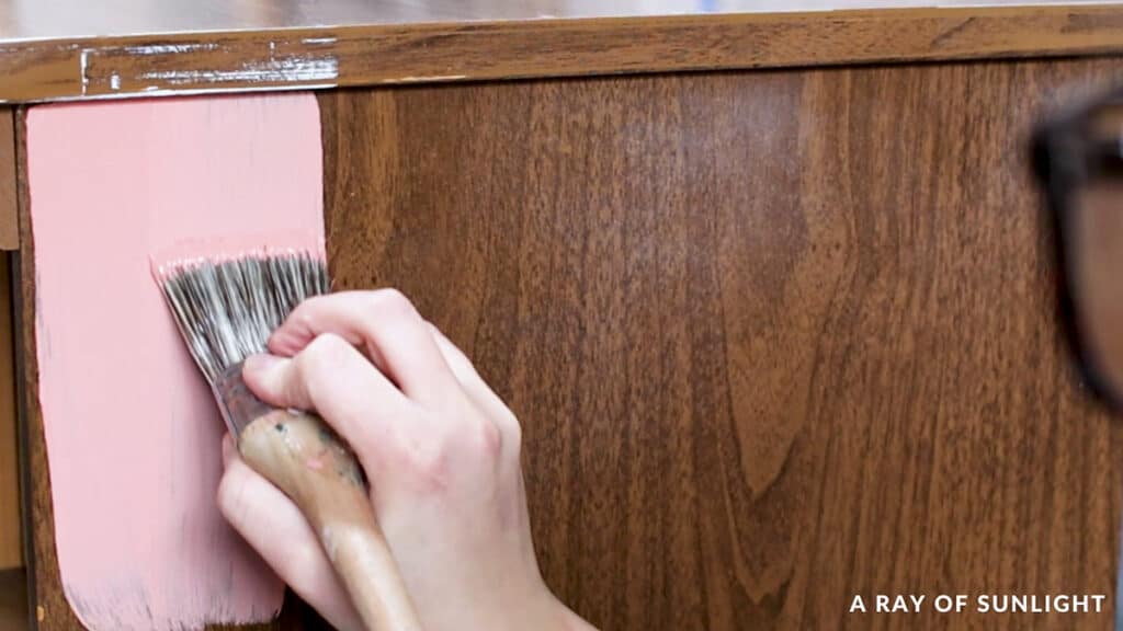 applying pink chalk paint with a paint brush