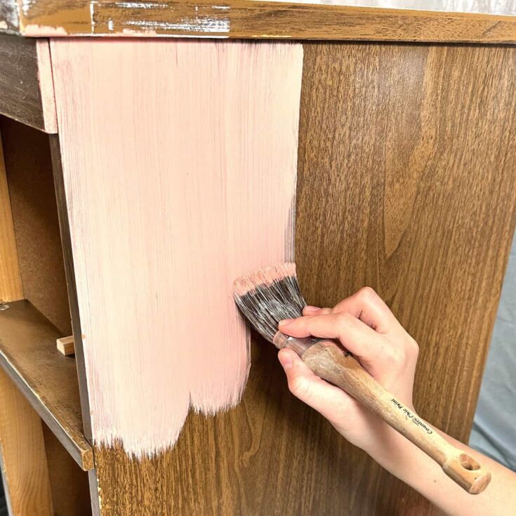 brushing some pink chalk paint onto the furniture