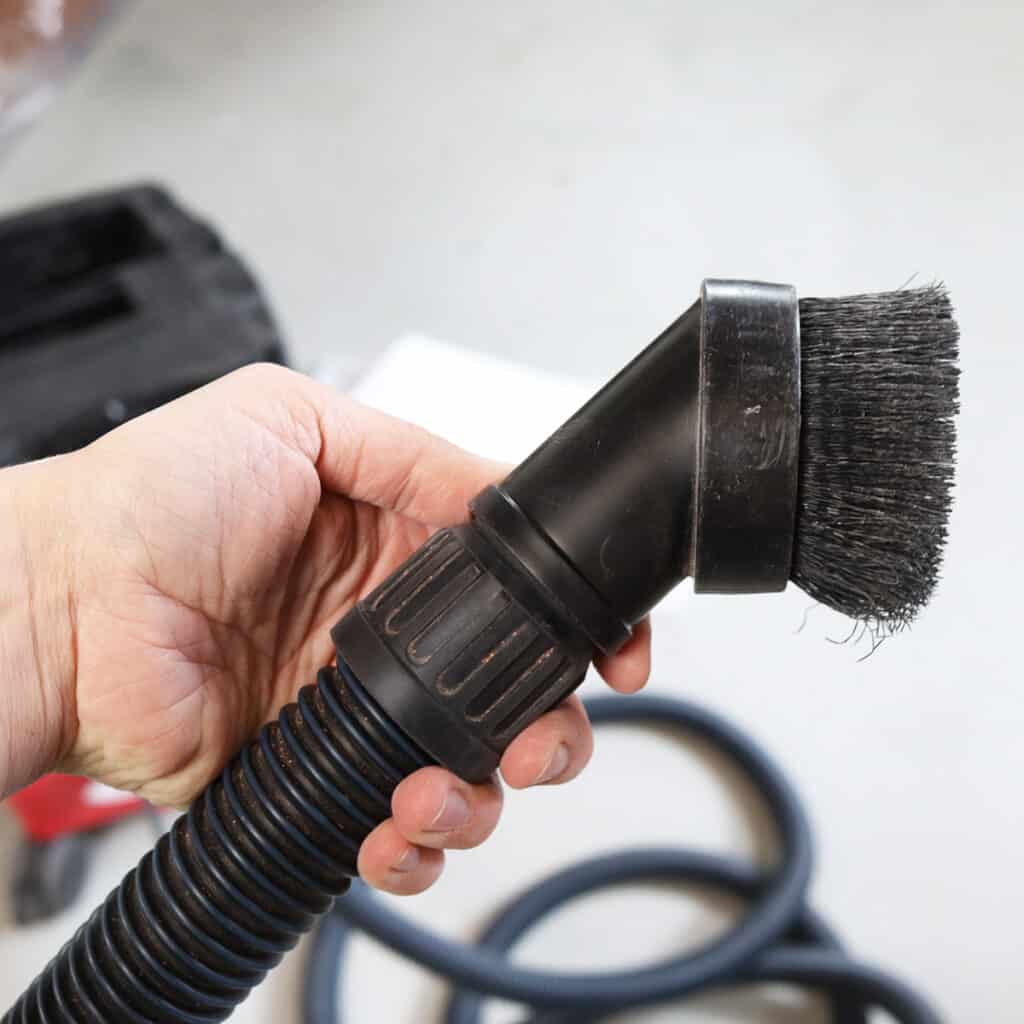 holding a brush attachment that sits on the end of the hose