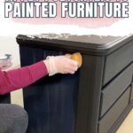 Natalie wearing a glove applies polycrylic to a dark painted dresser with a sponge applicator.
