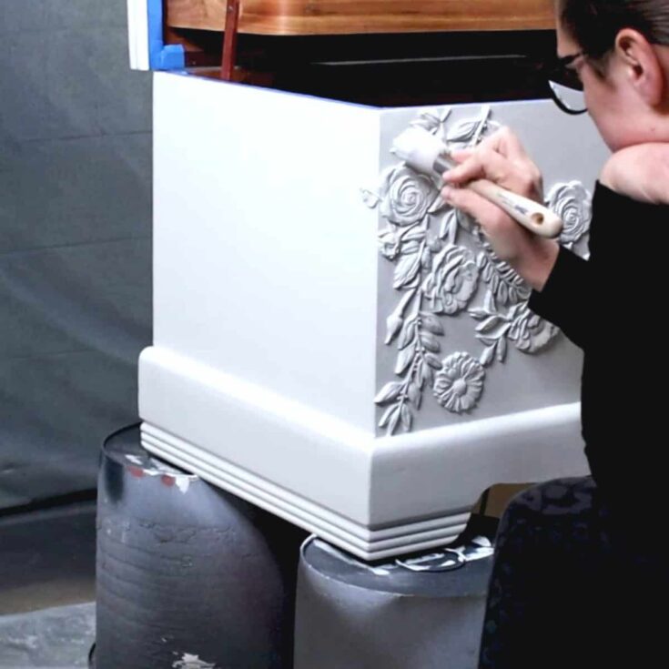 brushing gray paint onto cedar chest with resin moulds
