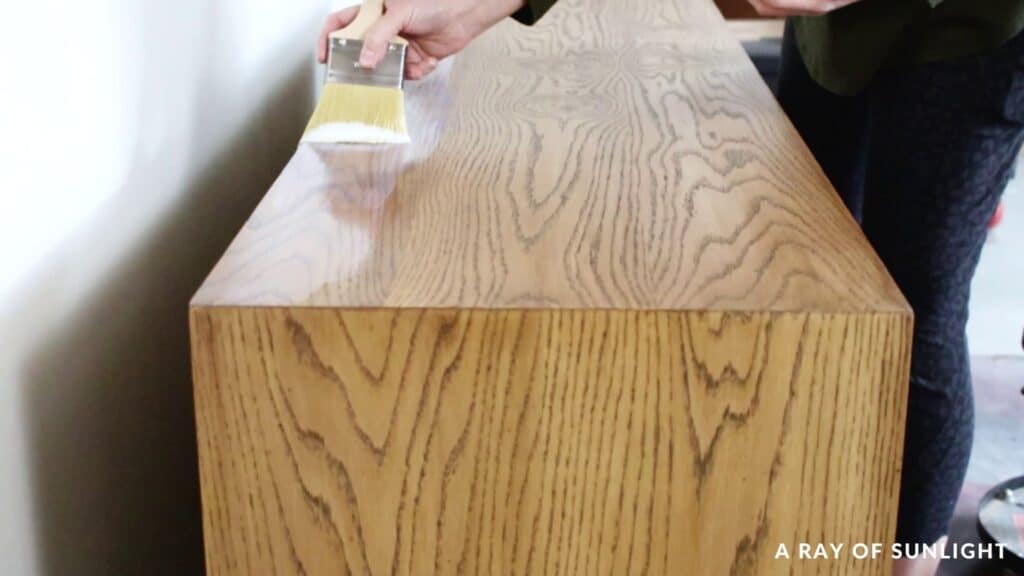 brushing waterbased polyurethane onto stained dresser