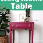 pink painted sewing machine table with decor, plants, and a framed quote on top, on a wood floor.