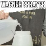 A person pours liquid from a plastic jug into a paint sprayer container on a white table.