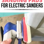 Hand using an electric sander with a foam sanding pad on a piece of furniture.