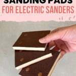 A hand holds three brown foam sanding pads for electric sanders against a light background.