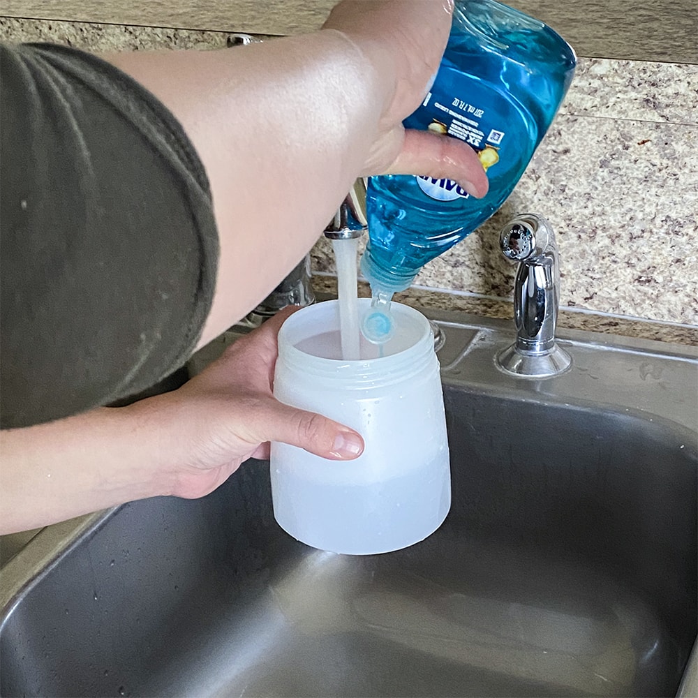 pouring liquid soap with warm water to clean the sprayer