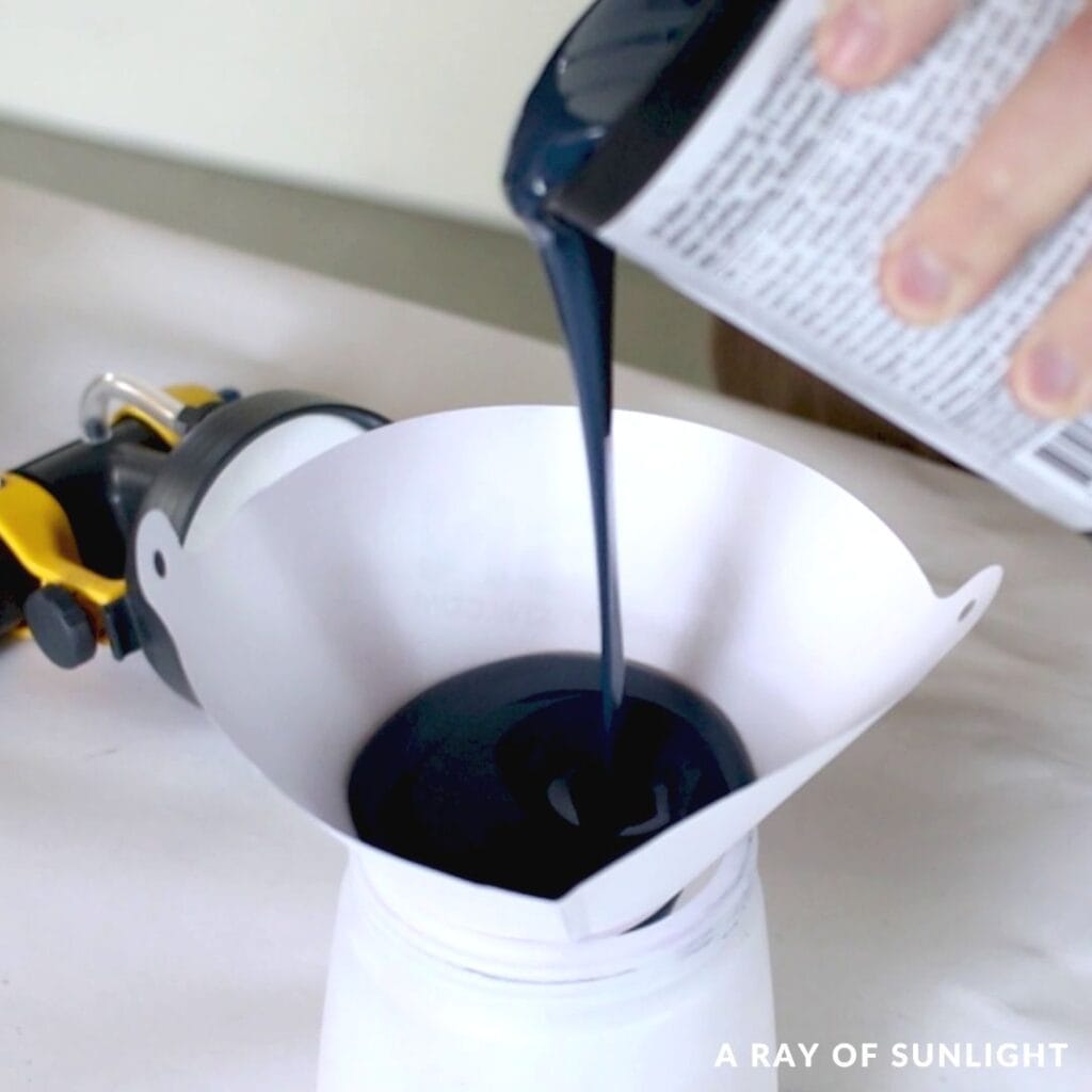 pouring paint into the sprayer container through a filter
