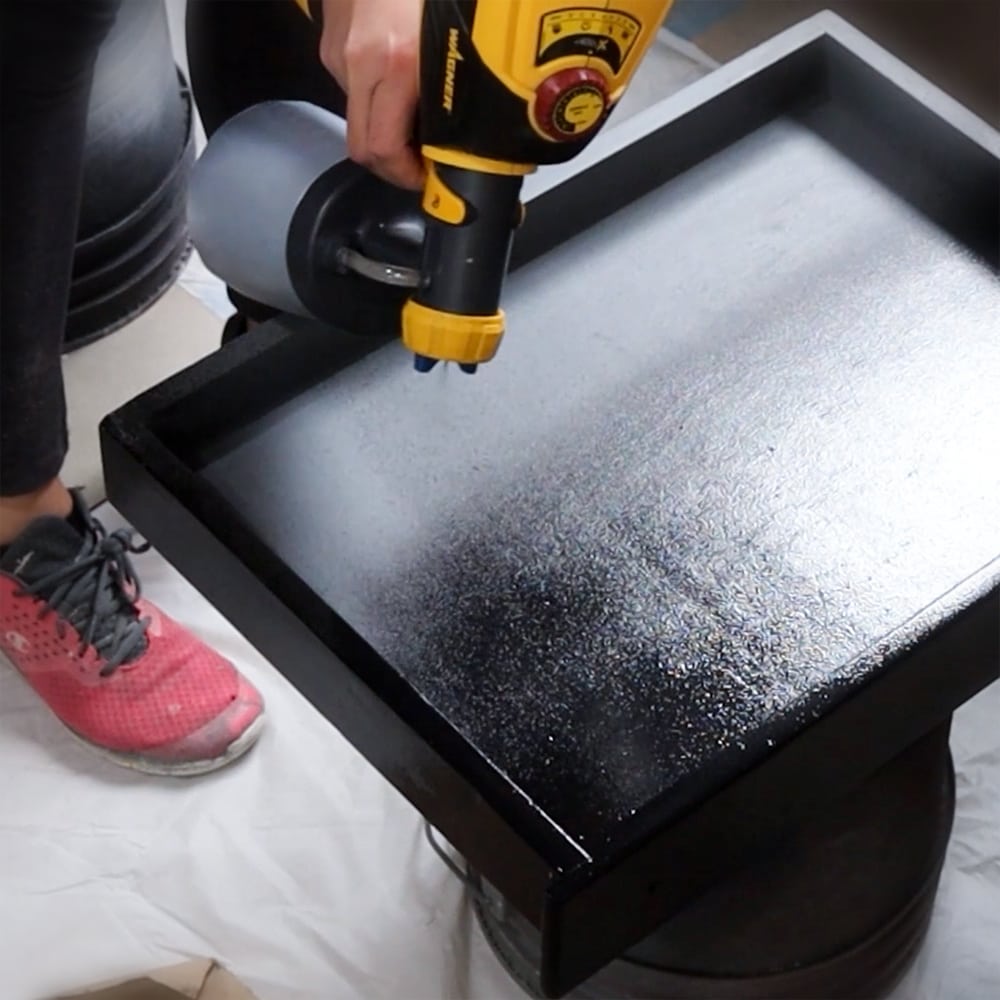 spraying black fusion paint with a paint sprayer