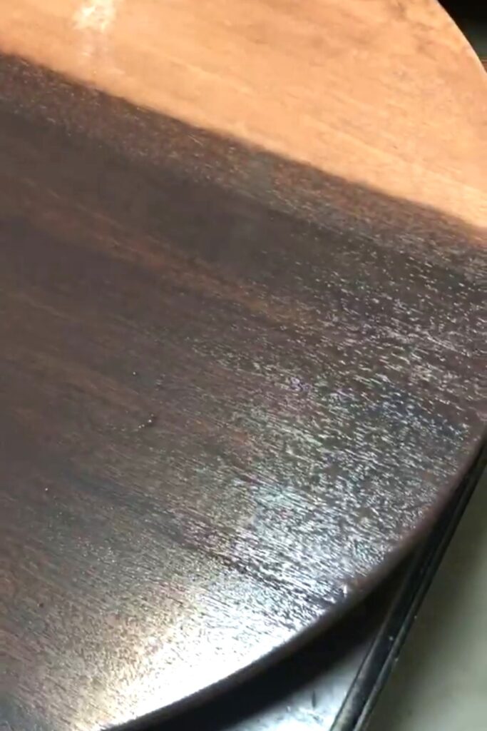brushing black paint onto wood to create a stained look