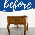 A wooden side table with curved legs under a bold blue before graphic.
