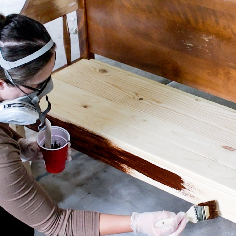 applying wood stain onto wooden bench with high quality brush