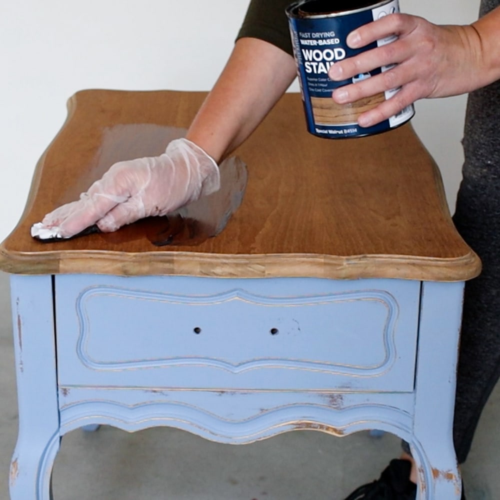 applying wood stain on top of the nightstand