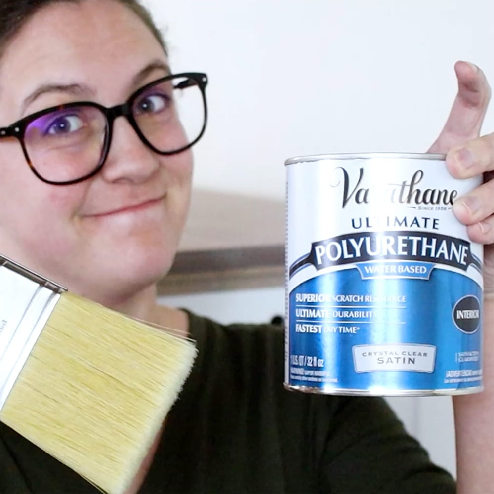photo of Natalie holding a can of  polyurethane and a high quality brush