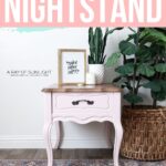 Pink-painted nightstand with decor items, a plant, and framed art on top, beside a woven basket.