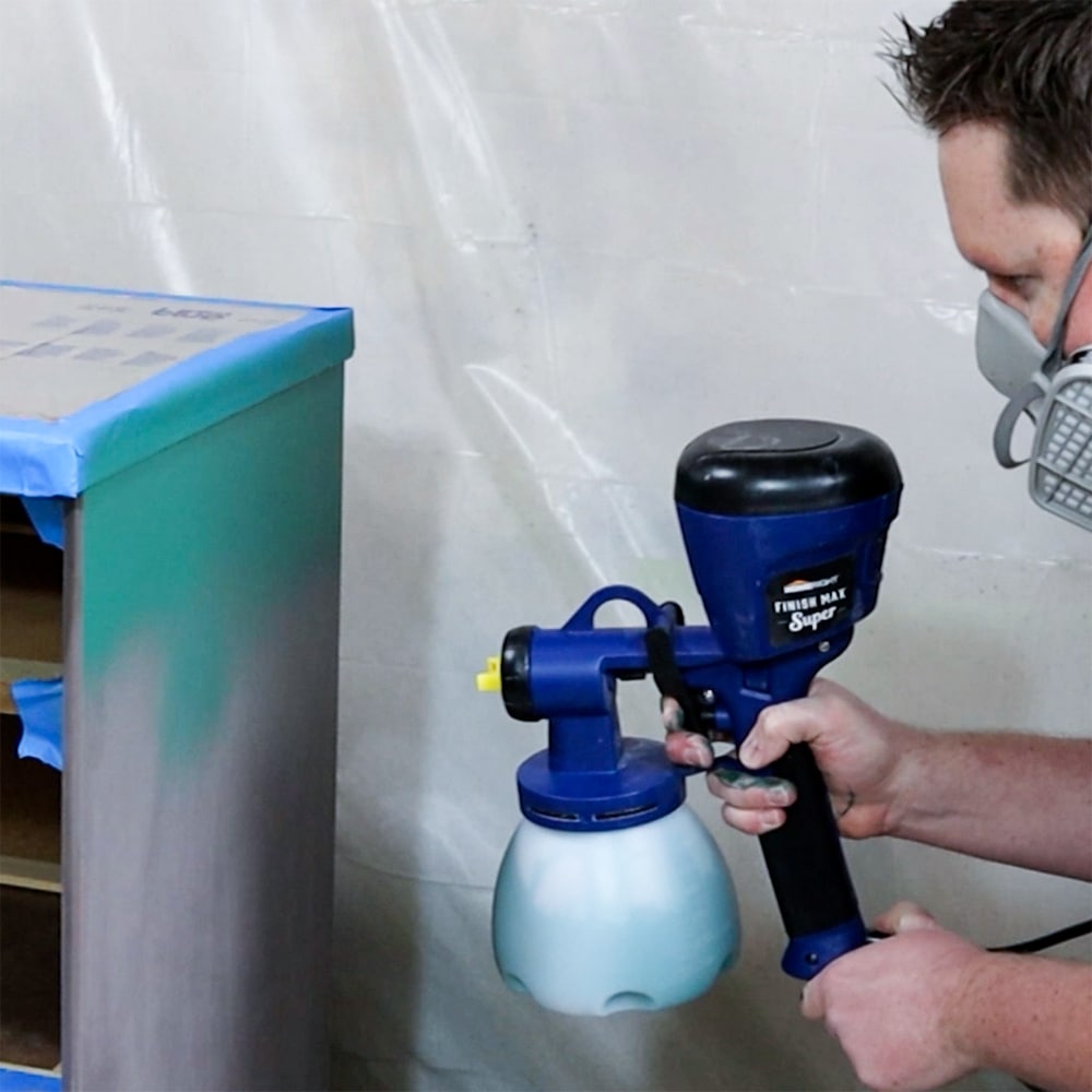 spraying paint onto furniture with a paint sprayer